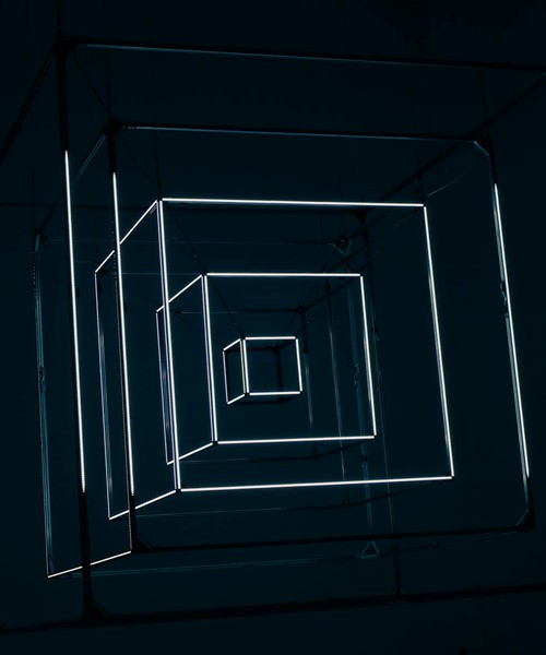 Modern art installation with geometric neon light shapes in dark setting.